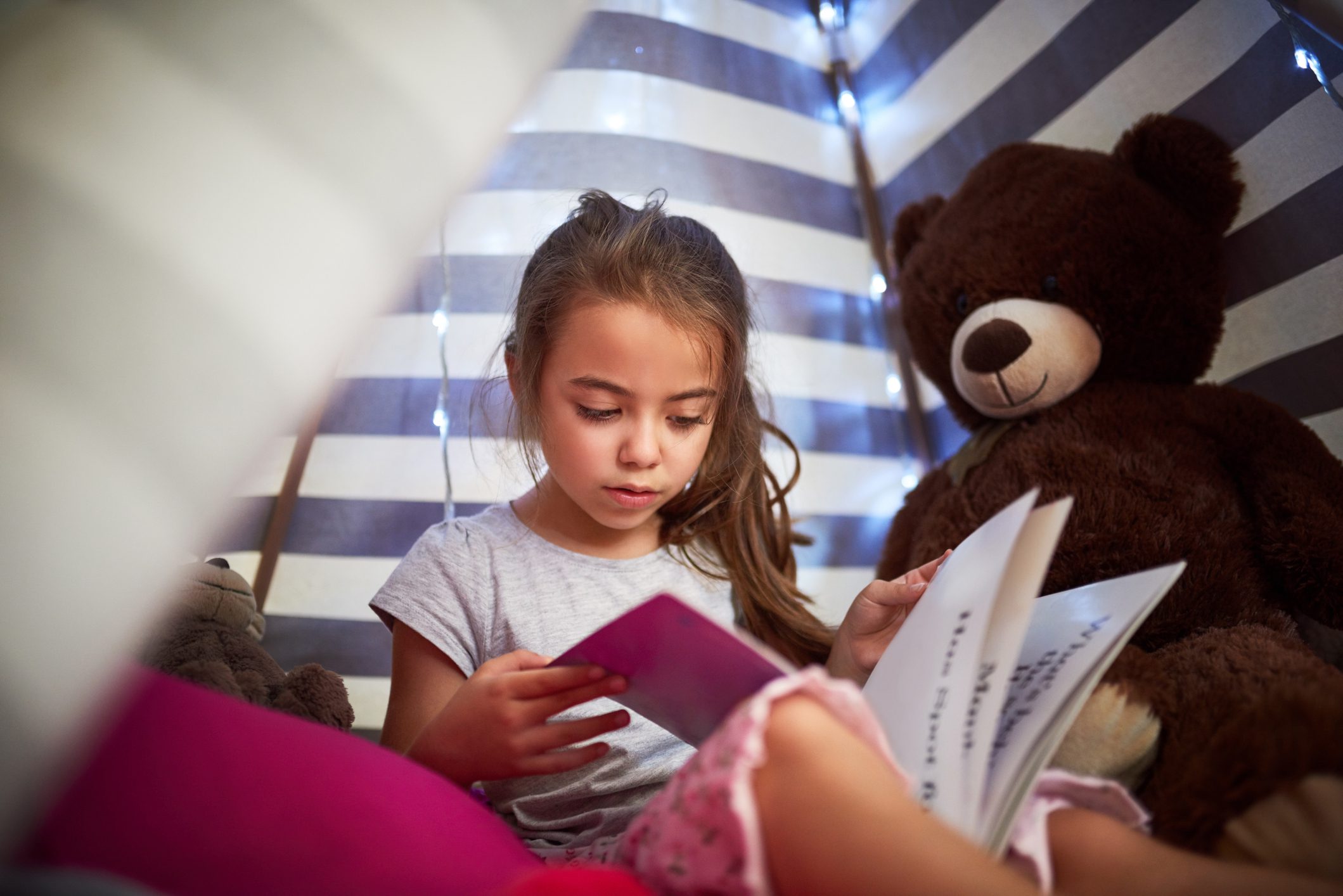 Child in a tent reading.